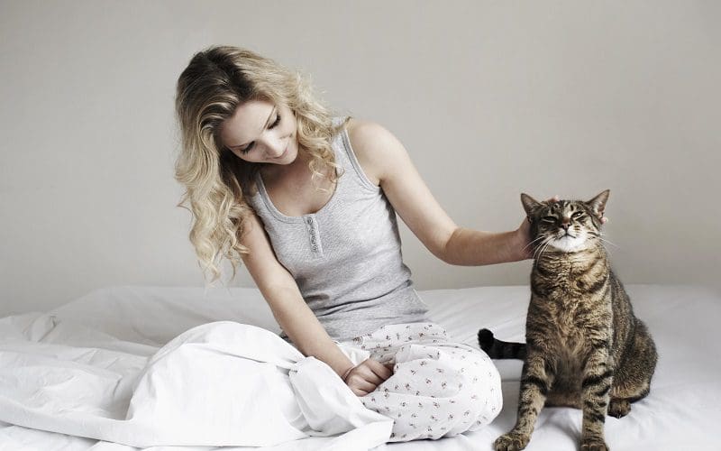 cuddling with cat on a bed